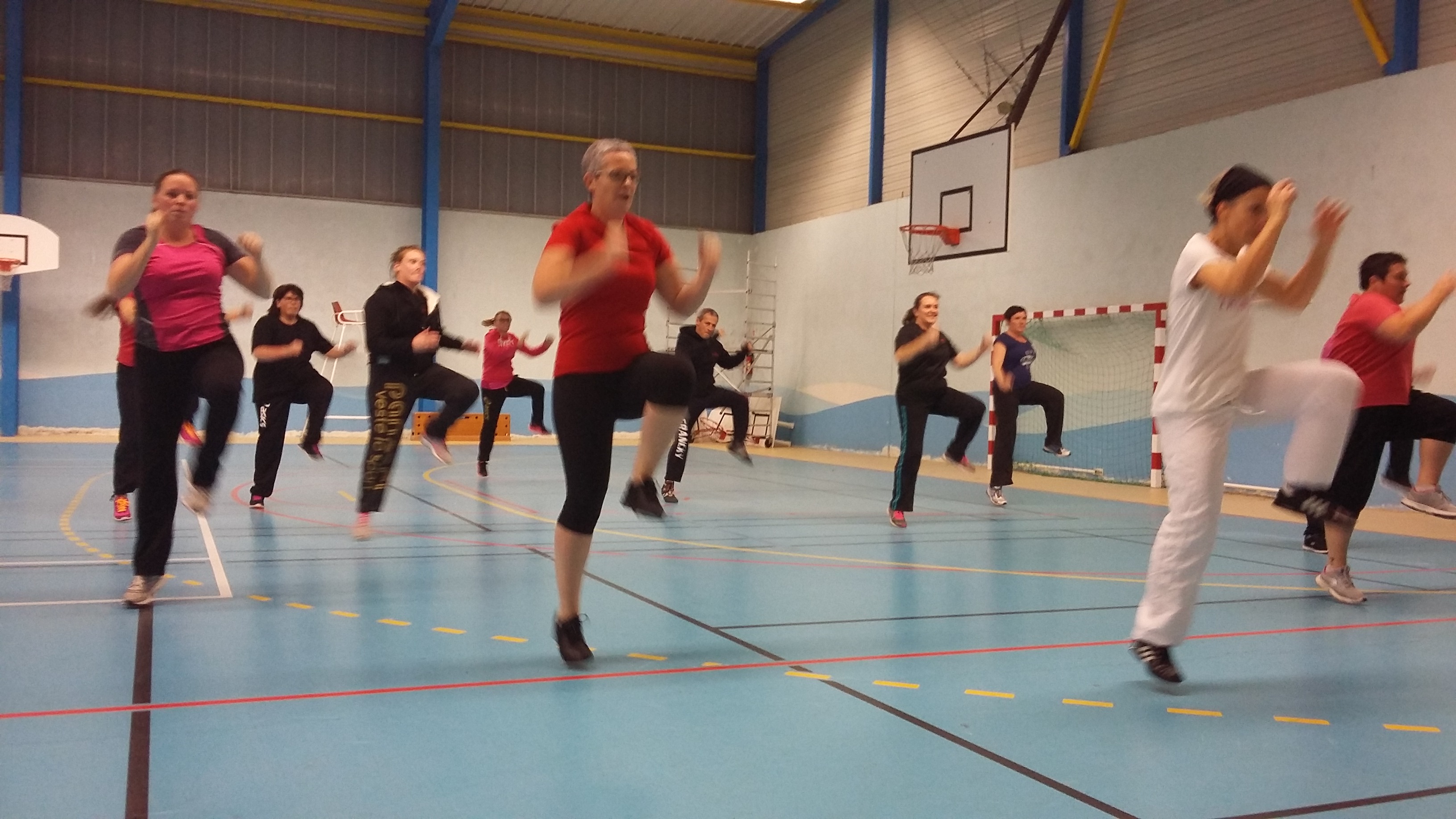 Un cours collectif du club, les participants genoux levés en rythme